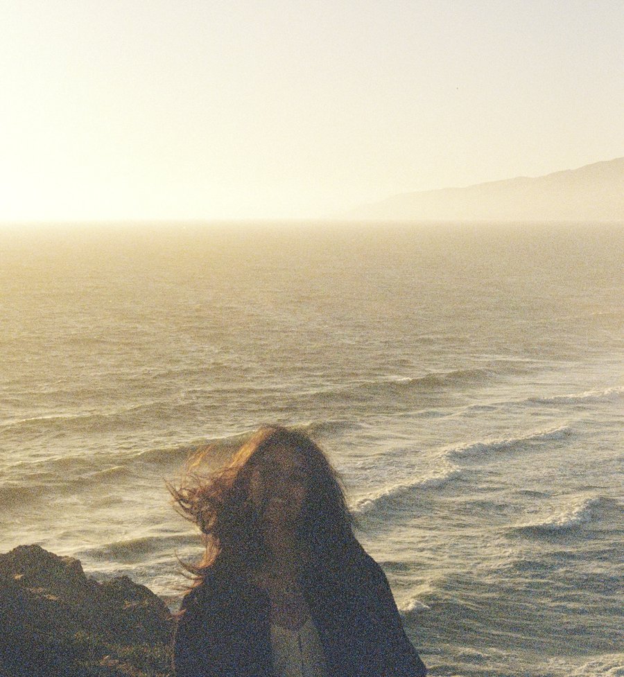Rafa with windswept hair against the ocean at golden hour