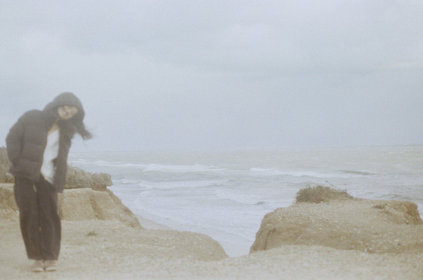 Standing on rocks along a hazy coastline