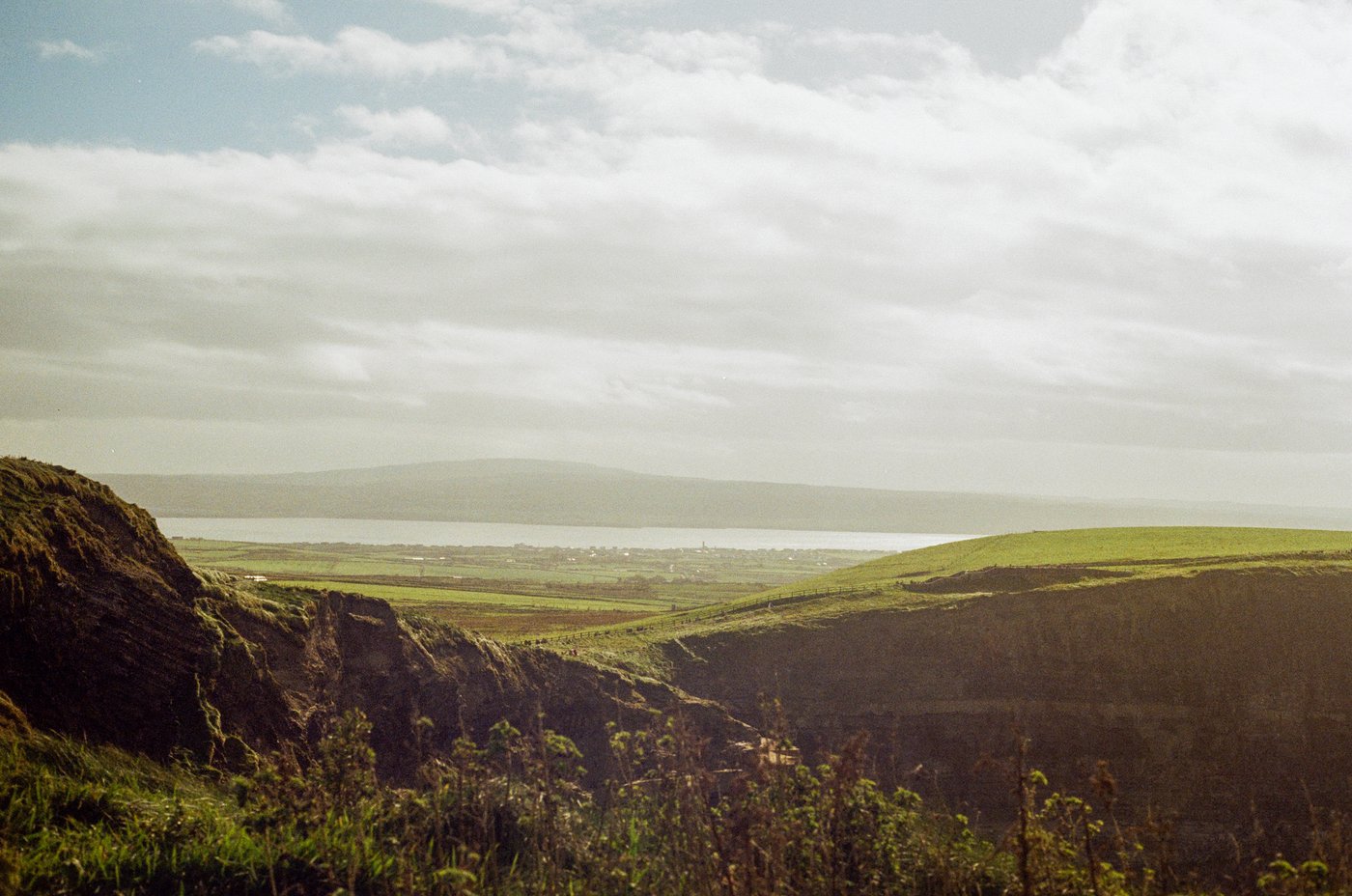 Cliffside view over green fields and a bay in Ireland