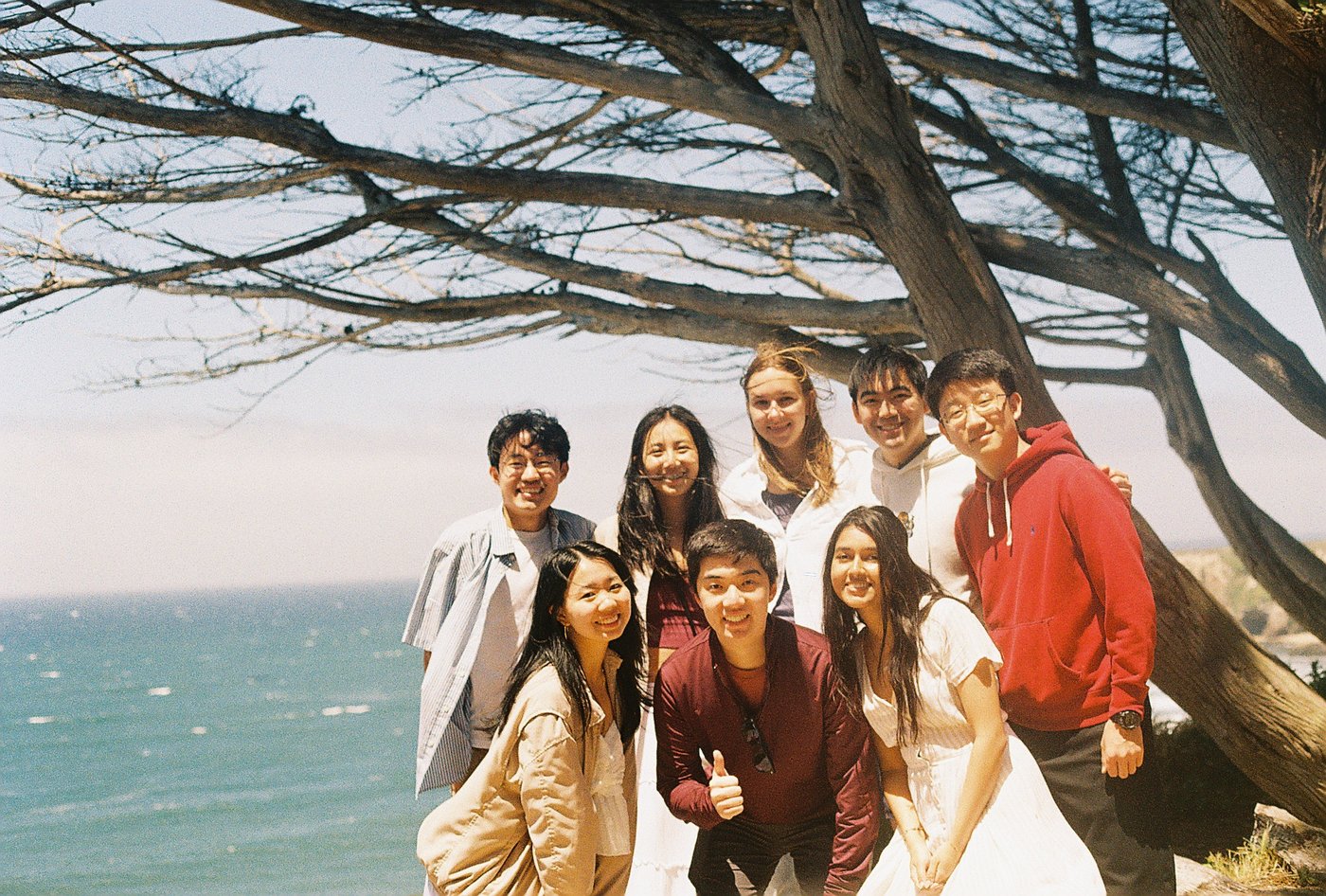 Friends posing under a tree by the water