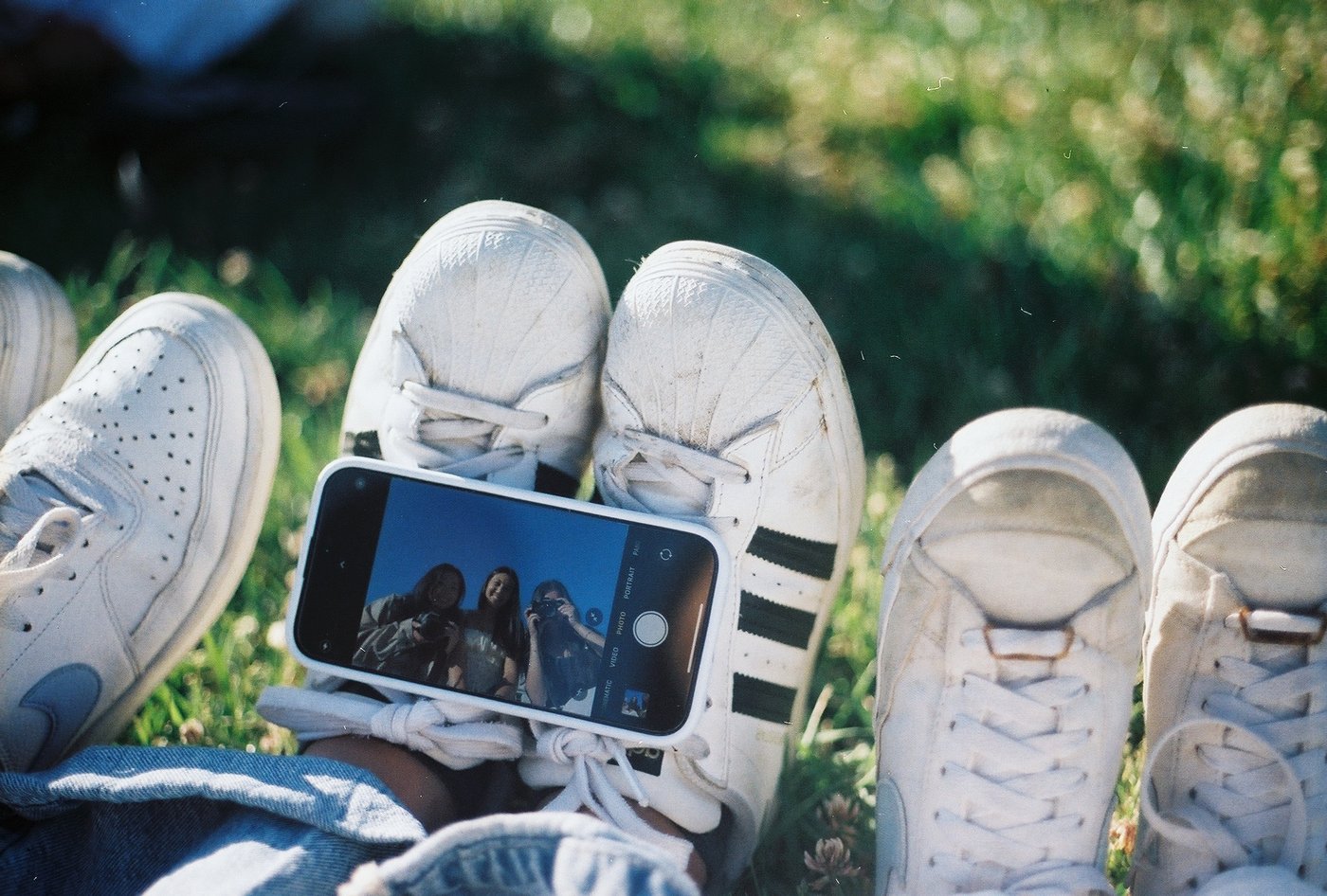 Sneakers and a phone taking a photo on the grass