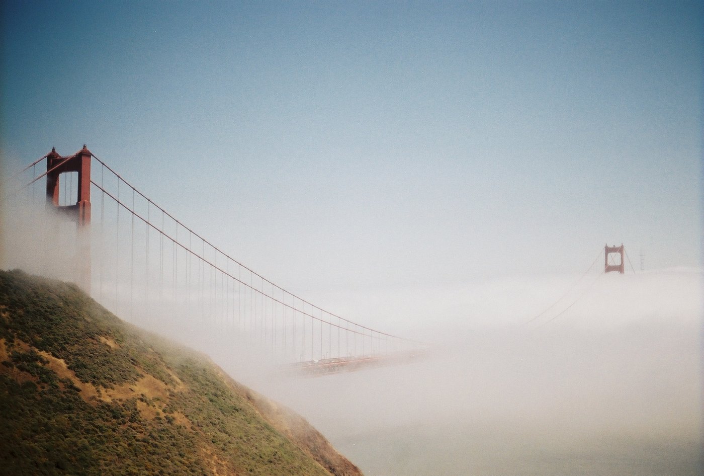 The Golden Gate Bridge in the fog with a sailboat