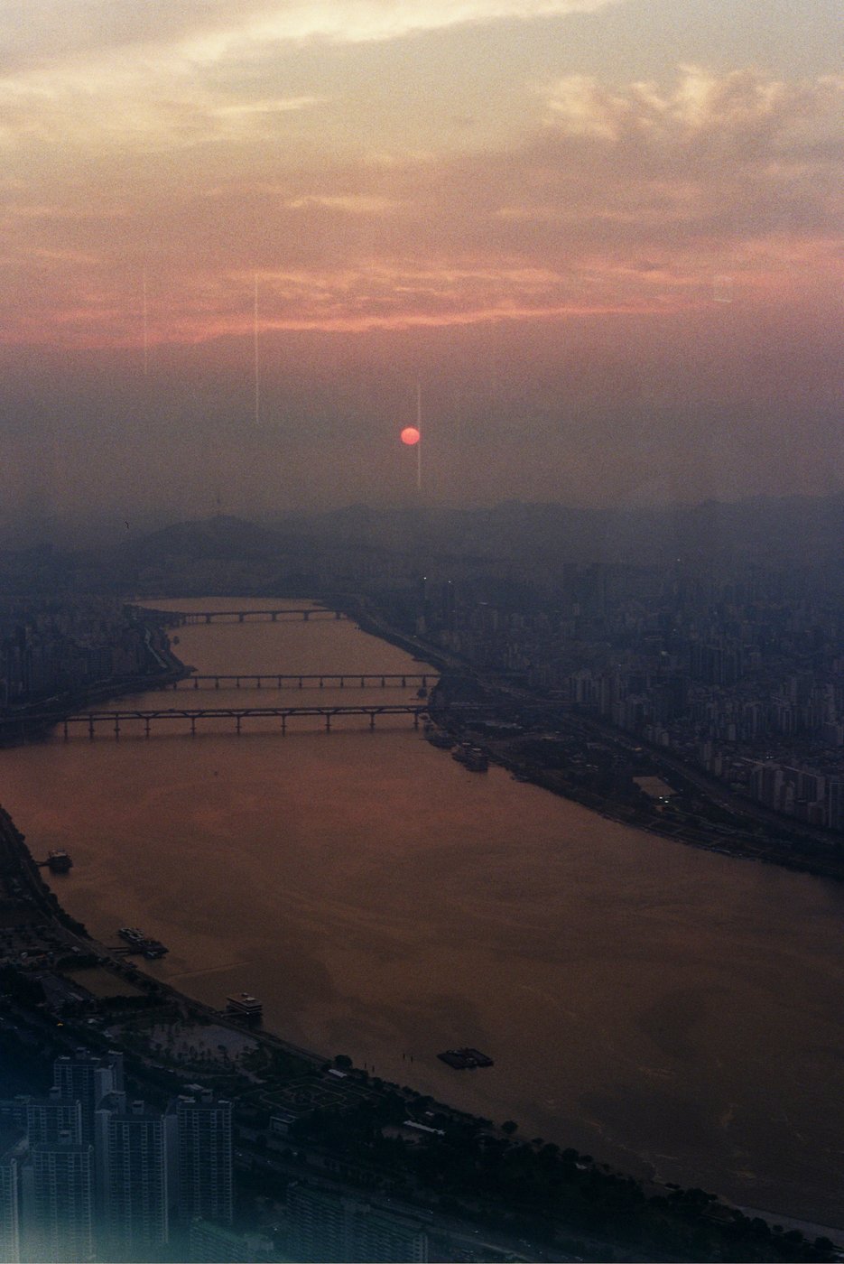 Sunset over a river with a bridge and city skyline