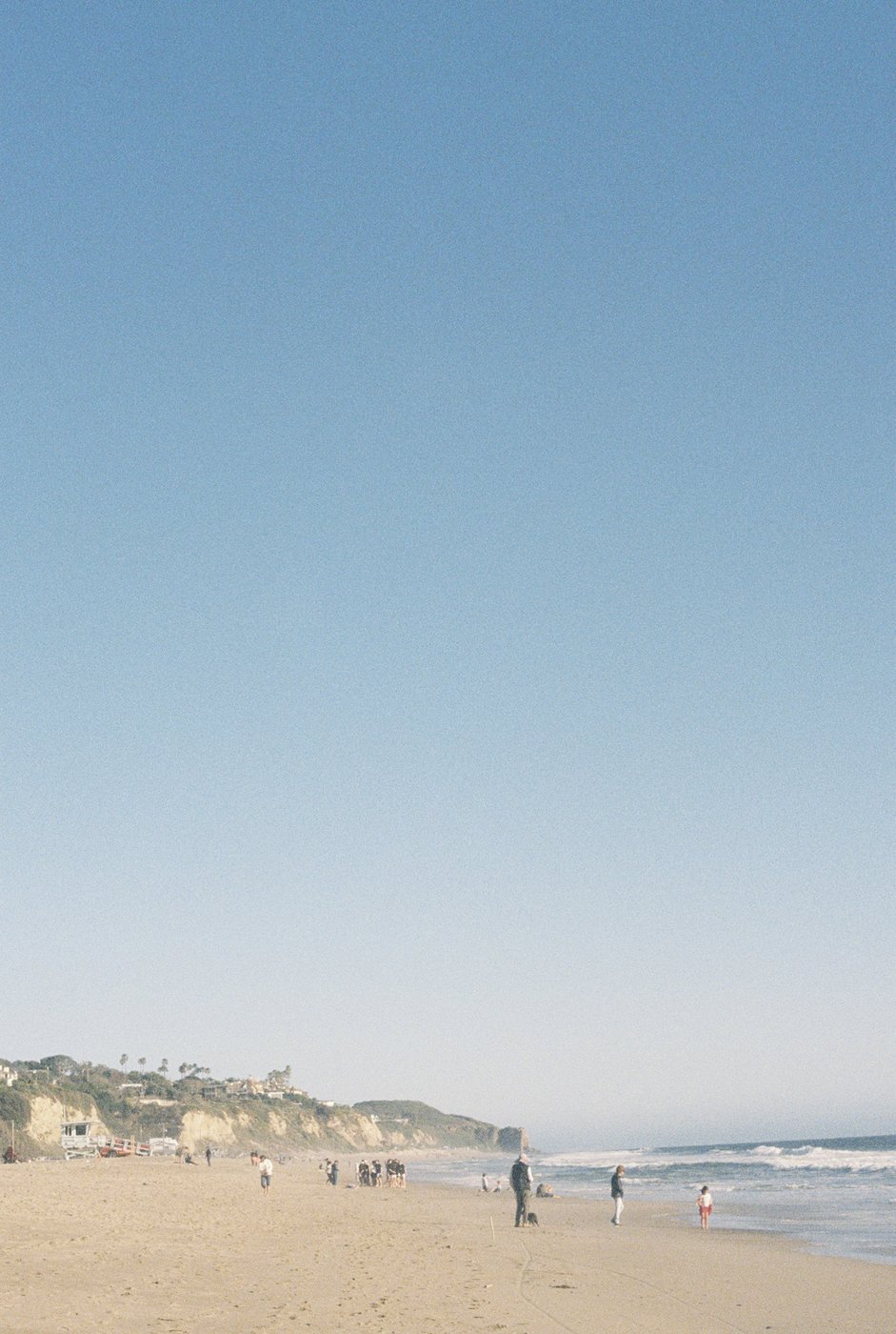 A beach with people walking along the shore